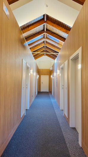 Ein Flur mit Holzwänden, schrägen Decken und Teppichboden.