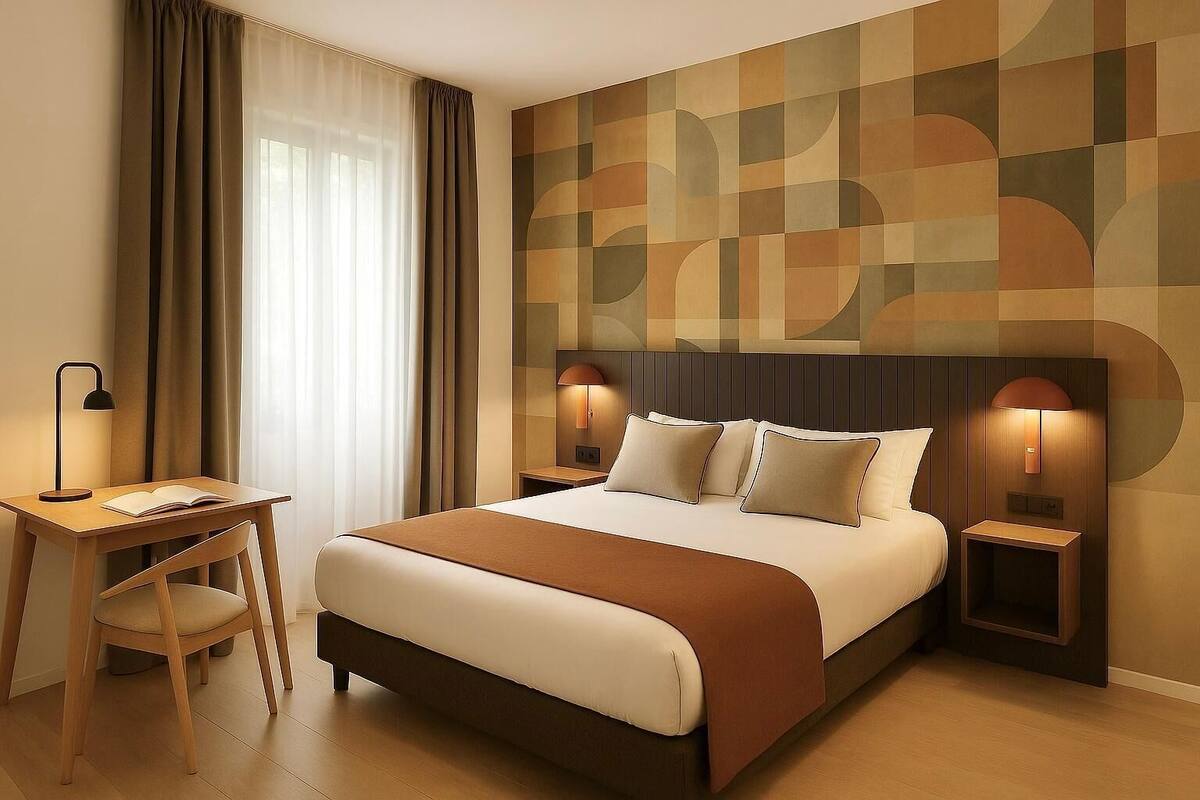 Una habitación de hotel con una cama grande, dos mesitas de noche con lámparas, un escritorio con silla y una ventana con cortinas.