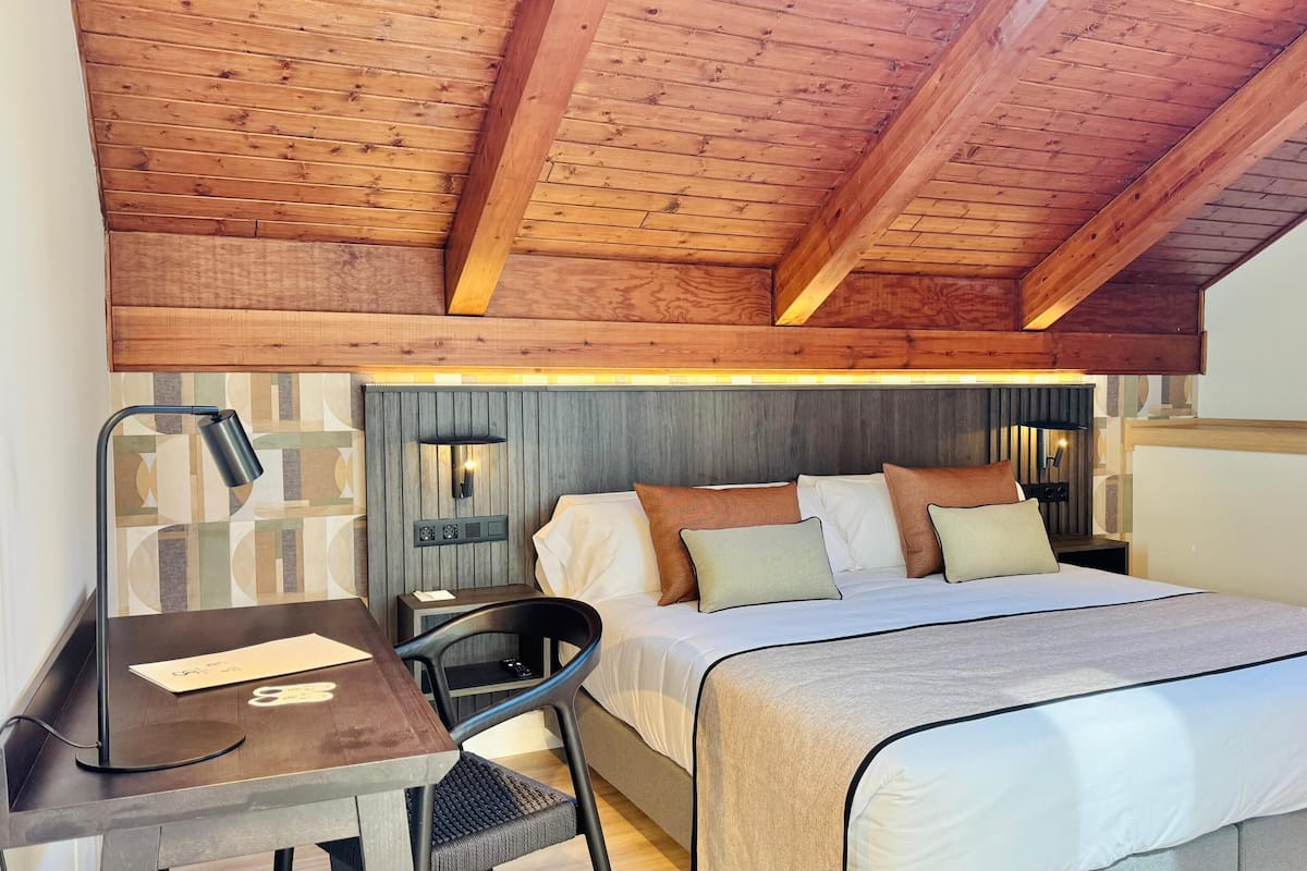 Un dormitorio con cama, mesitas de noche, escritorio y una silla.