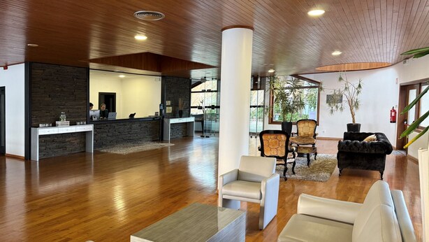 A spacious lobby with wooden flooring, a reception desk, seating area, and potted plants. - Hotel E Spa Alfândega Douro Valley (Alfandega da Fe)