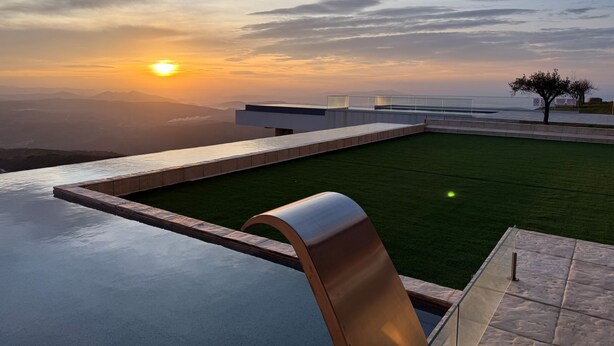 A modern rooftop terrace with a view of the sunset over a valley.