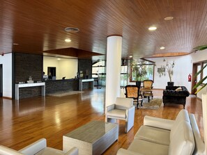 A spacious lobby with wooden flooring, a reception desk, seating area, and potted plants. - Hotel E Spa Alfândega Douro Valley (Alfandega da Fe)