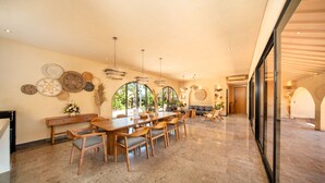 A spacious dining area with a long wooden table and chairs, a bench, and a wall adorned with decorative plates. - Cabana Kedungu Villa By Ini Vie Hospitality (Payangan)