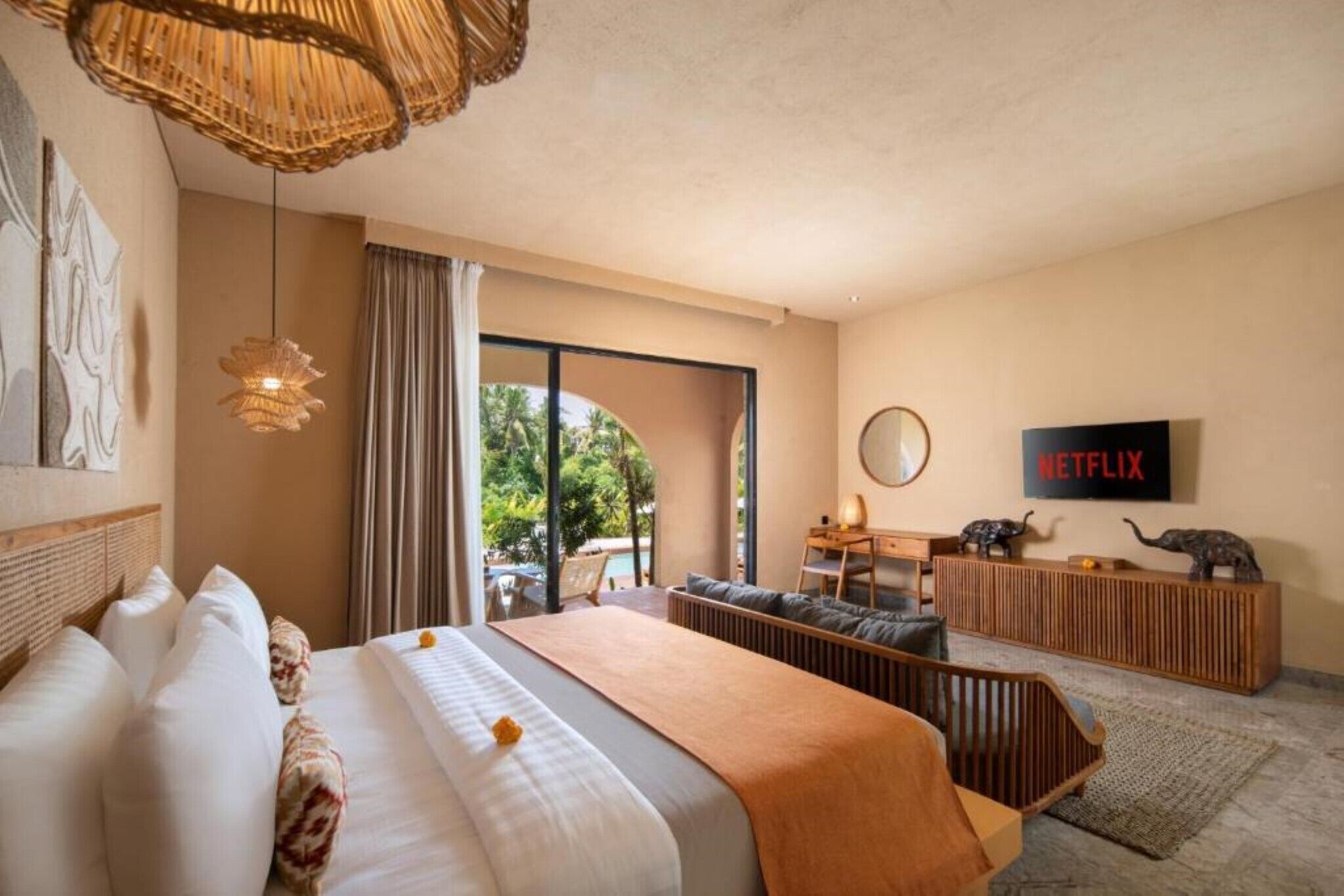 Ein Hotelzimmer mit einem großen Bett, einem Schreibtisch, einem Fernseher und Blick ins Freie.