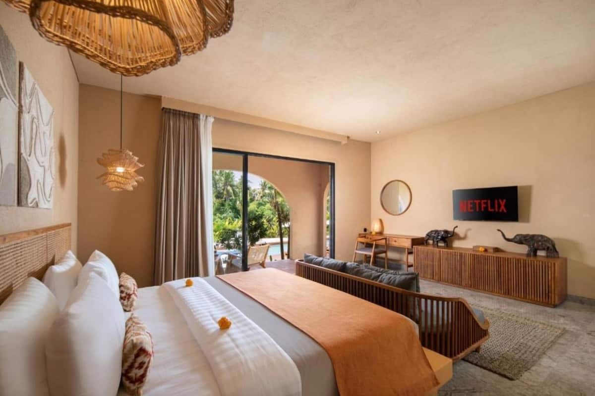 A hotel room with a large bed, a desk, a television, and a view of the outdoors.