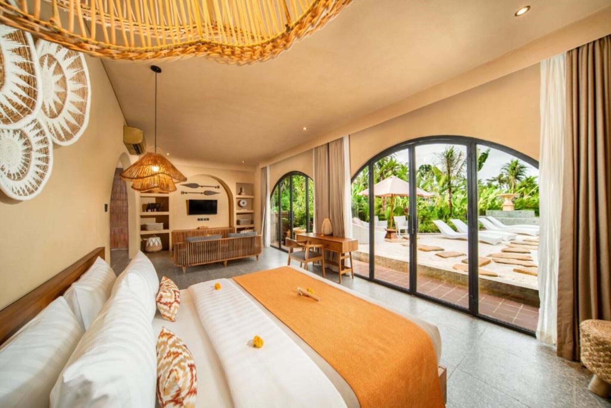 Ein geräumiges Schlafzimmer mit einem großen Bett, einem Schreibtisch und Blick auf den Außenpool.