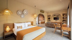 A hotel room with a bed, bedside lamps, a TV, a desk, and a dining area. - Cabana Kedungu Villa By Ini Vie Hospitality (Payangan)