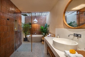 Ein modernes Badezimmer mit freistehender Badewanne, großem Waschbecken und Spiegel.