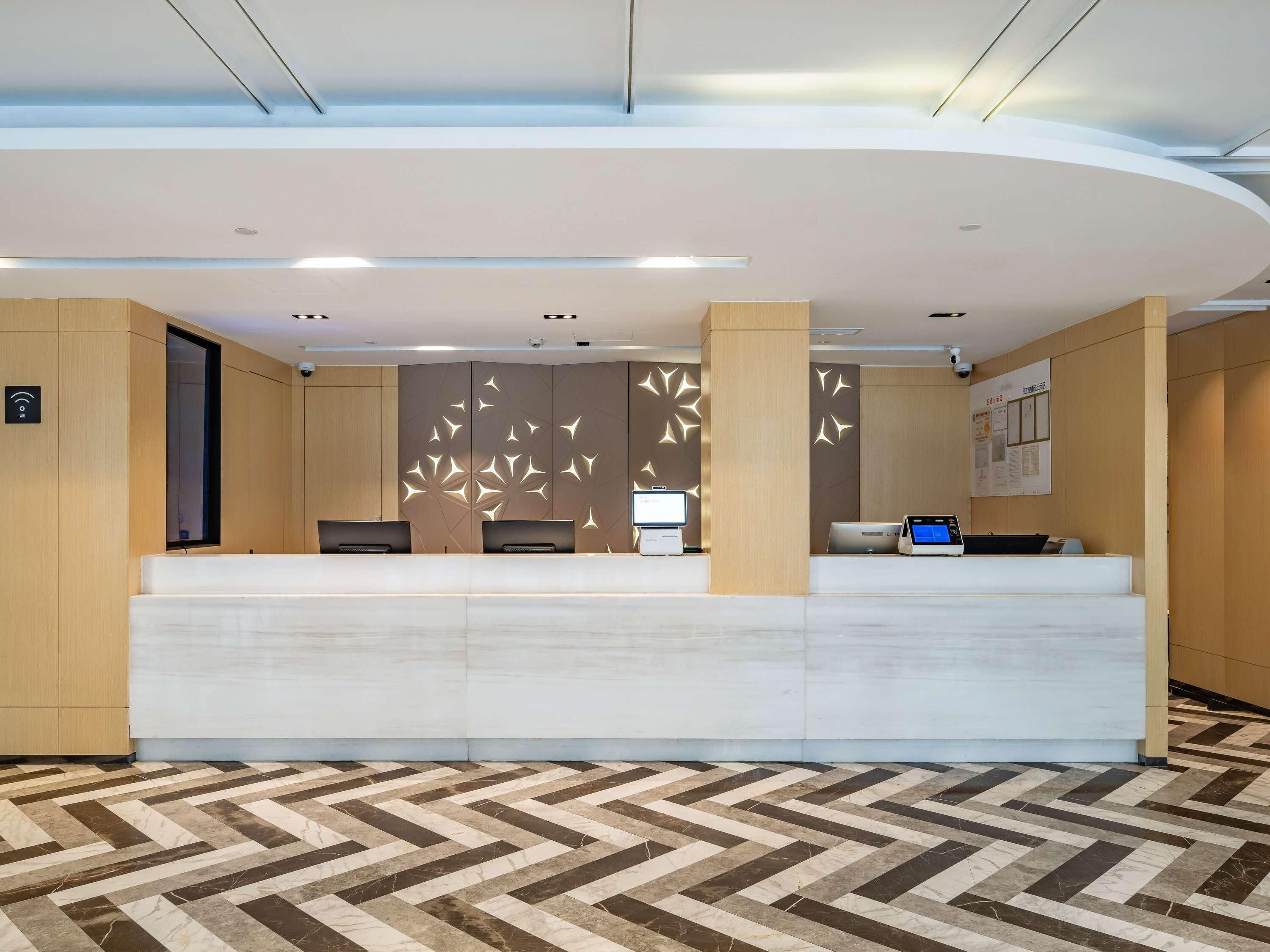 A reception desk with a modern design, a patterned floor, and a ceiling with recessed lighting.