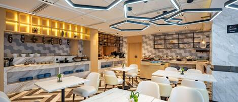 Un ristorante moderno con pavimento in marmo, tavoli e sedie bianchi. Presenti anche luci a soffitto esagonali e un'area cucina con buffet.