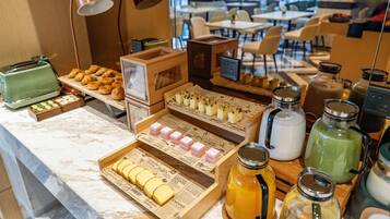 A breakfast buffet with pastries, sandwiches, and beverages.