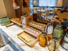 Un bufé de desayuno con pasteles, sándwiches y bebidas.