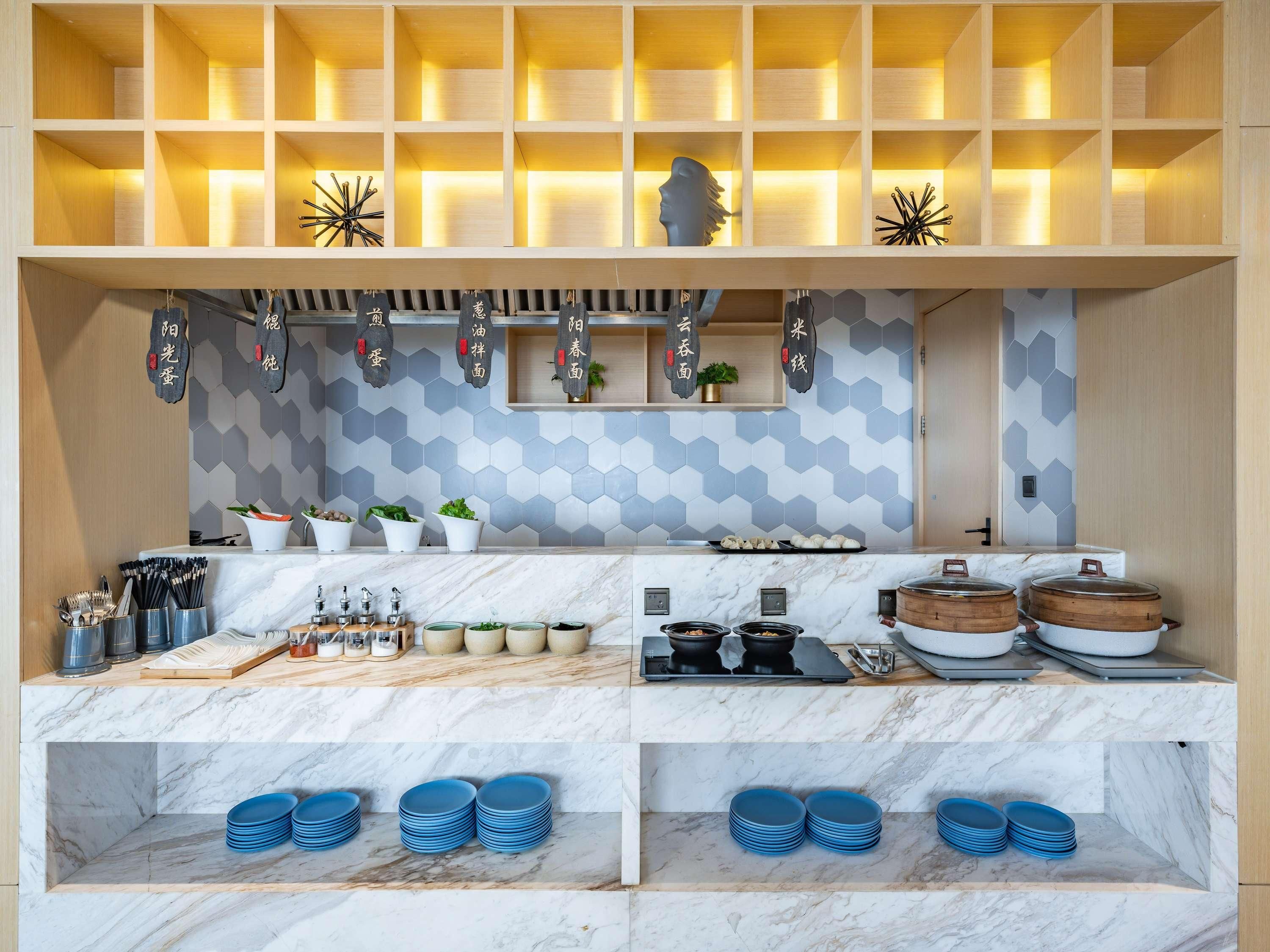 A modern kitchen with marble countertops, a hexagonal tile backsplash, and wooden shelves.
