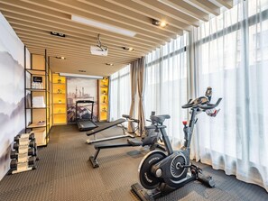 A modern gym with exercise equipment, a projector, and a cityscape mural. - Mercure Shanghai Pudong Zhangjiang Park (Zhoushan)