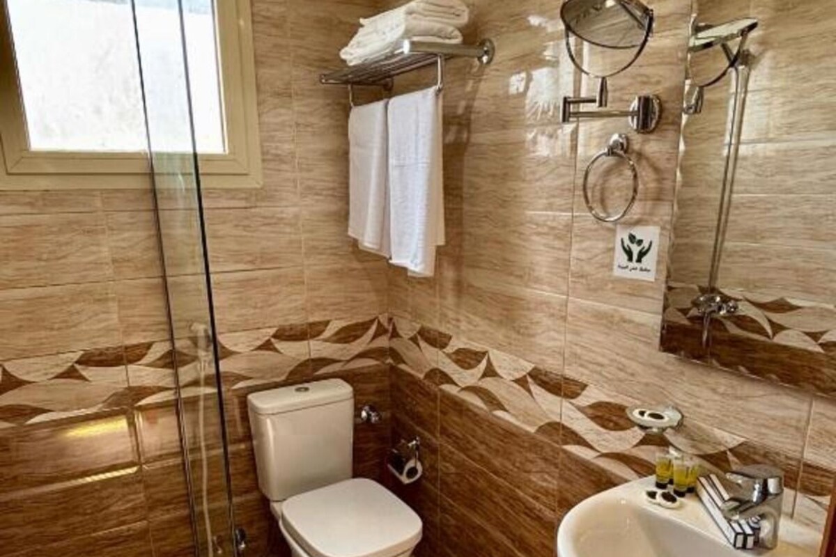 Een badkamer met een douchecabine van glas, toilet, wastafel en spiegel.