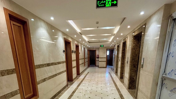 Un pasillo de hotel con pisos de mármol, puertas de madera y un letrero de salida.