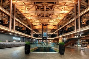 Un vaste atrium doté d’un haut plafond, d’un comptoir d’accueil et d’un élément décoratif central en forme de fontaine.