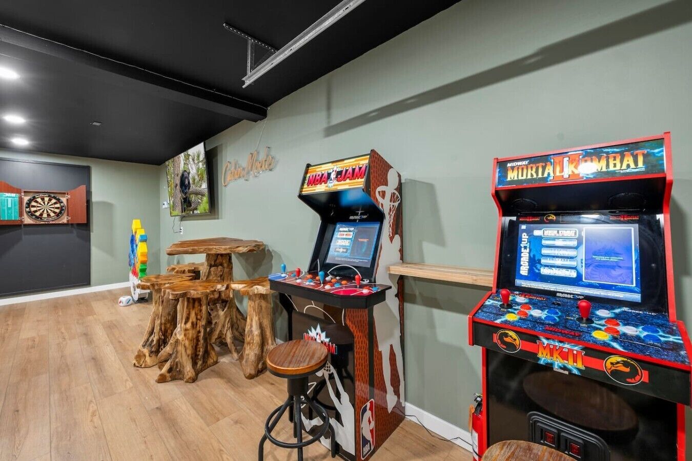 Una habitación con juegos arcade, un dardo y una mesa de madera.