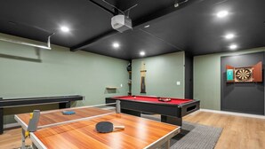Sala de lazer com mesa de bilhar, mesa de pingue-pongue e dardos.