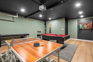 Ein Spielzimmer mit Billardtisch, Tischtennisplatte und Dartscheibe.