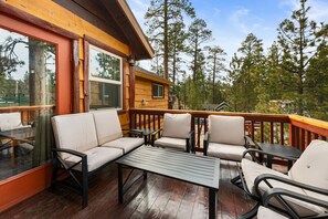 Eine Holzterrasse mit einer Couch, Stühlen und einem Tisch.