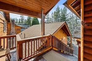 Eine Holzhütte mit Balkon, Treppe und Blick auf die umliegenden Bäume.