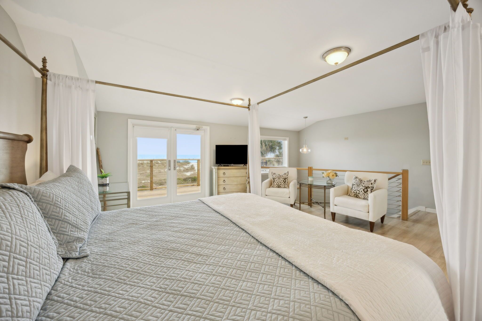 Un dormitorio con una cama grande, un escritorio y una silla. Se ve una ventana con vistas al exterior.