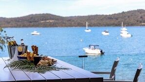 Ein Tisch mit Speisen und Getränken mit Blick auf einen See und Boote.
