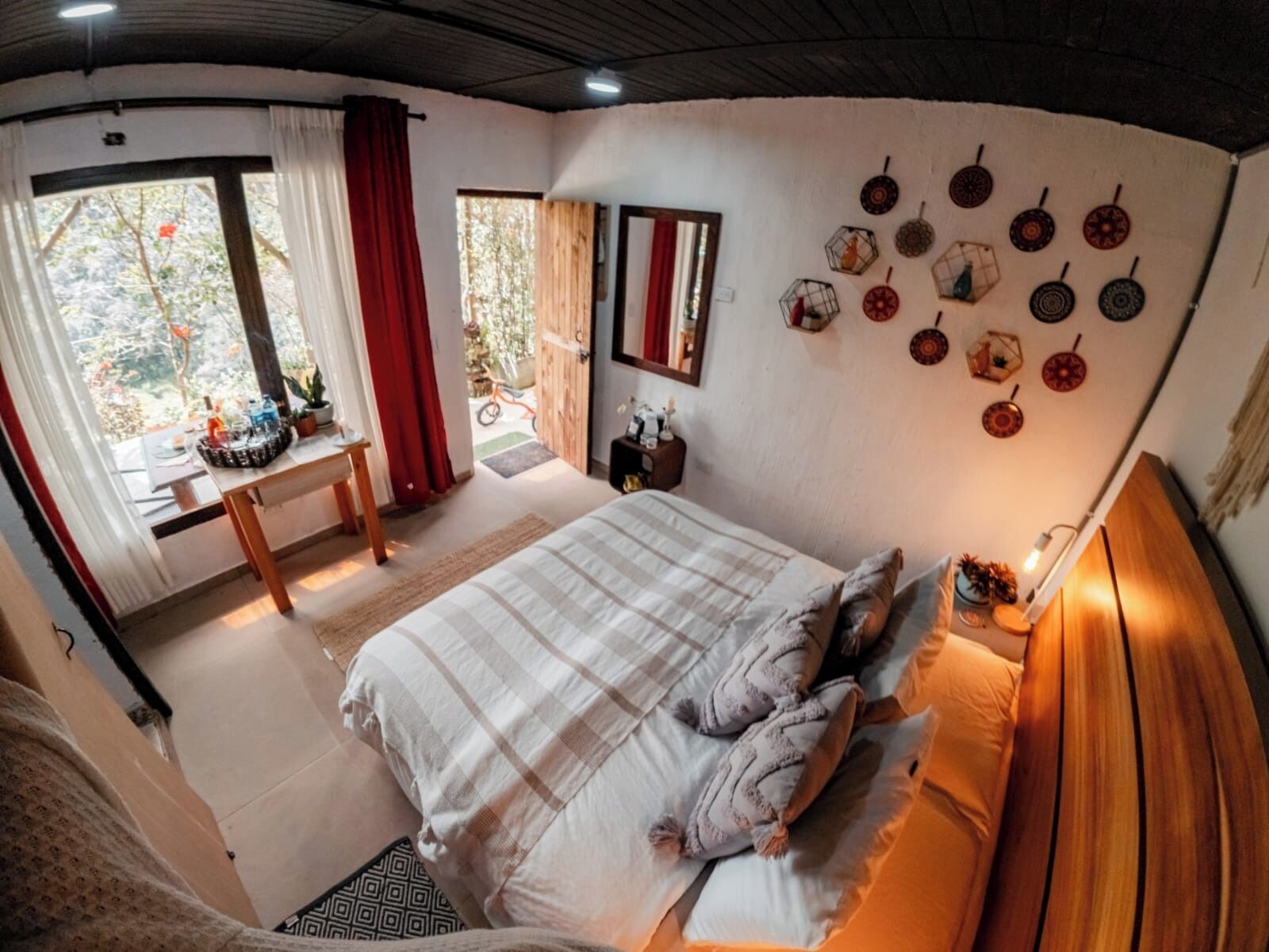 Un dormitorio con cama, escritorio y ventana con cortinas.