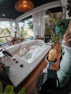 Un espace bien-être comprenant un bain à remous, une bougie et diverses plantes.