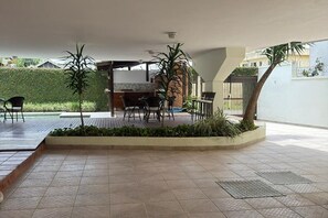 An outdoor patio area with a dining table and chairs, surrounded by planters and a small pool. - Enseada Beach, Guarujá - For 10 people (Guarujá)
