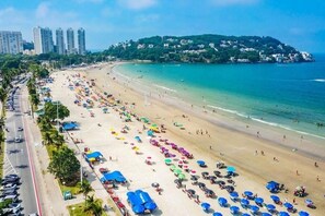 A beach with rows of umbrellas and beachgoers. - Enseada Beach, Guarujá - For 10 people (Guarujá)