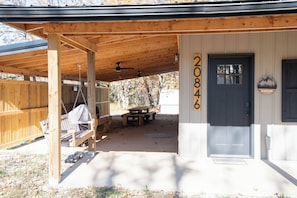 A wooden covered porch with a swing, a bench, and a picnic table. - Peaceful, NEWLY Constructed Barndominium Retreat Near Fort Leonard Wood (Waynesville)