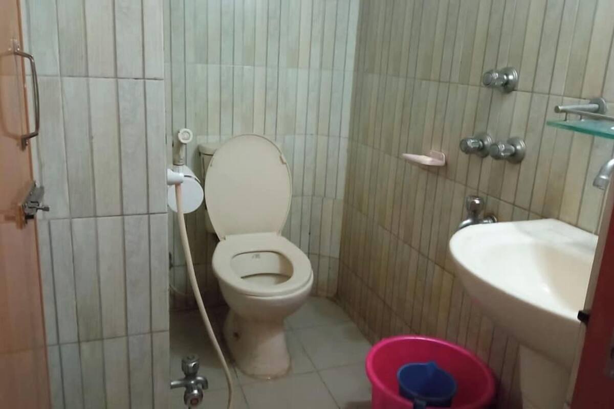 A small bathroom with a toilet, sink, and a red bucket.