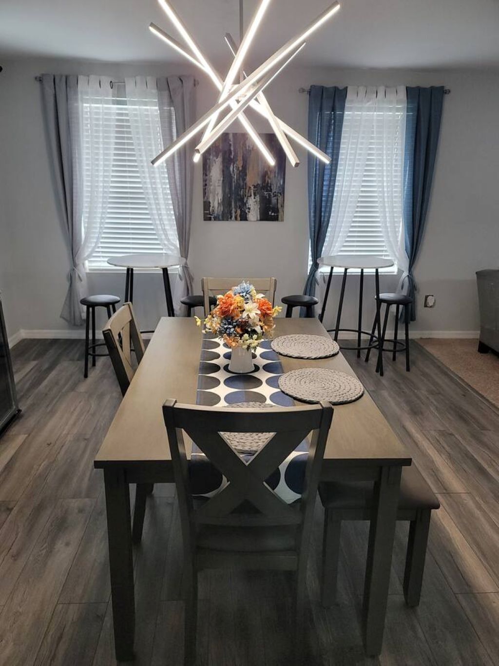 Un espace repas comprenant une longue table, des chaises, un arrangement floral central et un luminaire moderne.