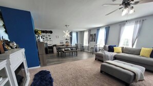 A modern living room with a sofa, ottoman, and a dining area with a table and chairs.
