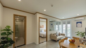 Une chambre d’hôtel moderne dotée d’une douche en verre, d’un lit, d’un canapé, d’une table à manger avec des chaises et d’une grande fenêtre.