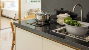 Une cuisine moderne dotée d’un plan de travail noir, d’appareils électroménagers en acier inoxydable et d’un évier muni d’une passoire.