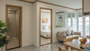 Une chambre d’hôtel moderne équipée d’une douche, d’un lit, d’un canapé, d’une table à manger et d’un grand miroir.