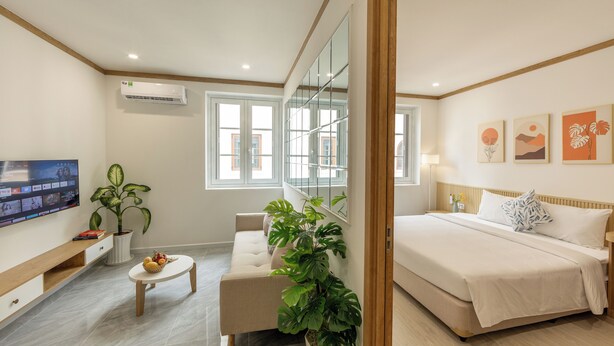 Une chambre d’hôtel moderne équipée d’un canapé, d’un lit, d’une télévision et de grandes fenêtres.