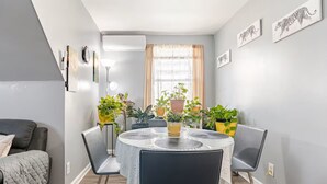 A dining area with a round table, chairs, and potted plants.
