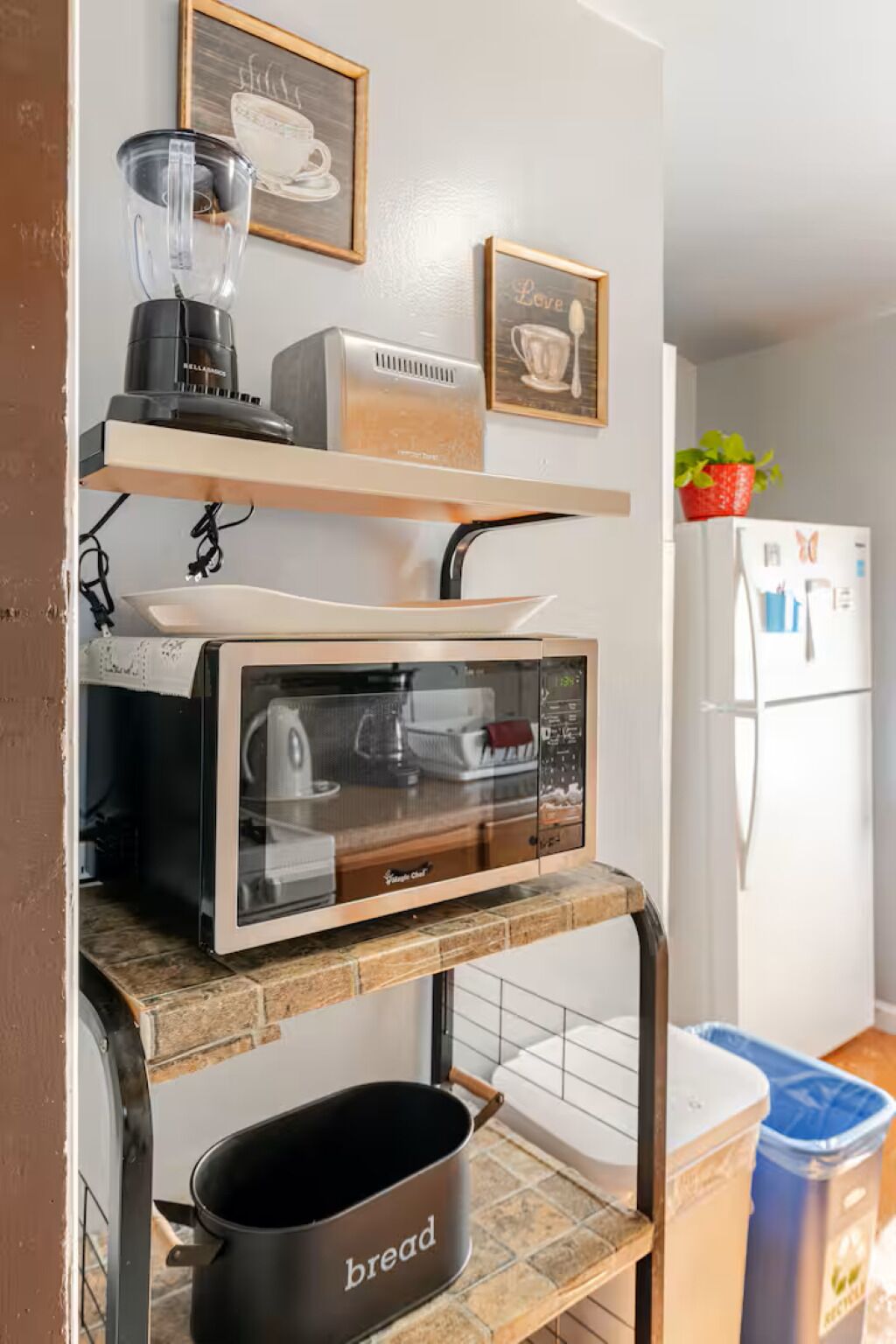 A kitchen with a built-in oven, a microwave, and a bread container on a shelf.