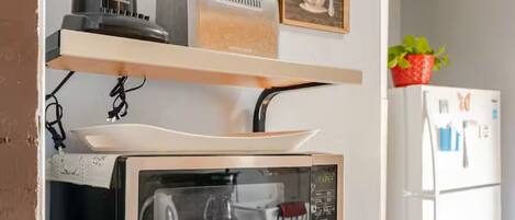 A kitchen with a built-in oven, a microwave, and a bread container on a shelf.