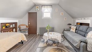 A cozy, well-lit room with a bed, a sofa, a small table, and a radiator.