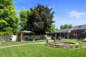 A backyard with a covered patio, a swimming pool, and a brick building. - Summer and Winter Getaway (Sandy)
