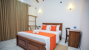 Ein Hotelzimmer mit einem hölzernen Bett, zwei Kissen, einem Nachttisch, einem kleinen Holzstuhl, einer Wasserflasche und einem Vorhang.