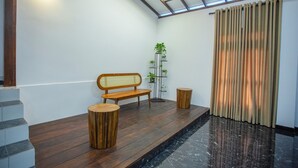 Ein modernes Interieur mit einer hölzernen Bank, zwei Hocker, einem Pflanzenregal und einer Treppe.