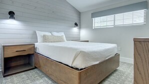 Ein Schlafzimmer mit einem hölzernen Bettgestell, zwei Nachttischen, einer Fensterbank und einer Wandleuchte.