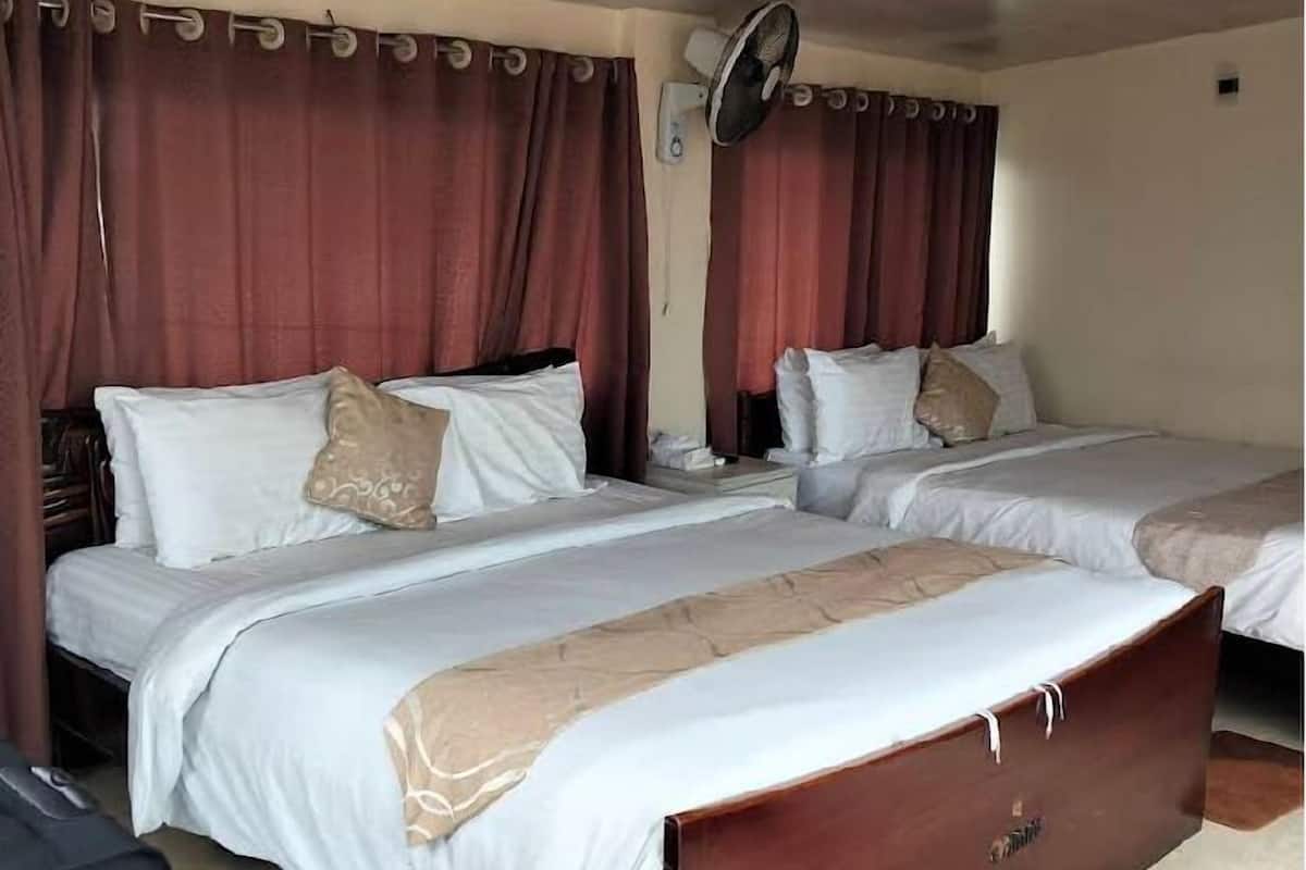 Ein Hotelzimmer mit zwei Betten, einem Deckenventilator und Vorhängen.