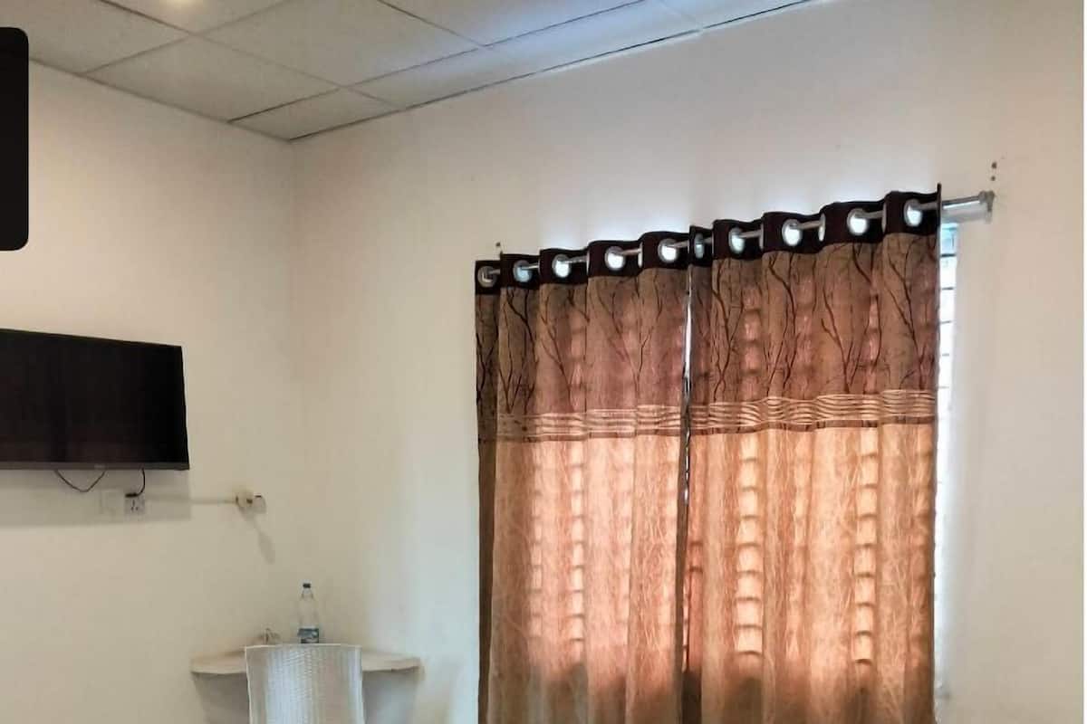 Ein Schlafzimmer mit einem Bett, einem Schreibtisch und einem Fernseher an der Wand.